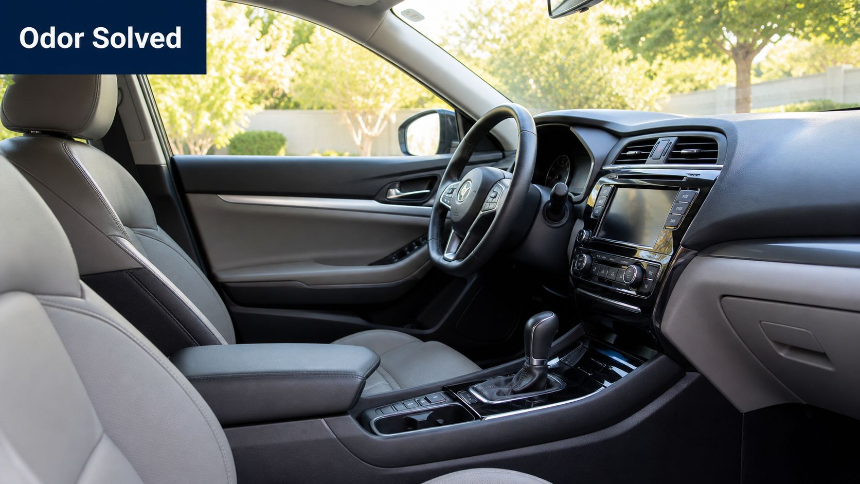 A clean interior view of a modern sedan, featuring grey leather seats and a organized dashboard.
