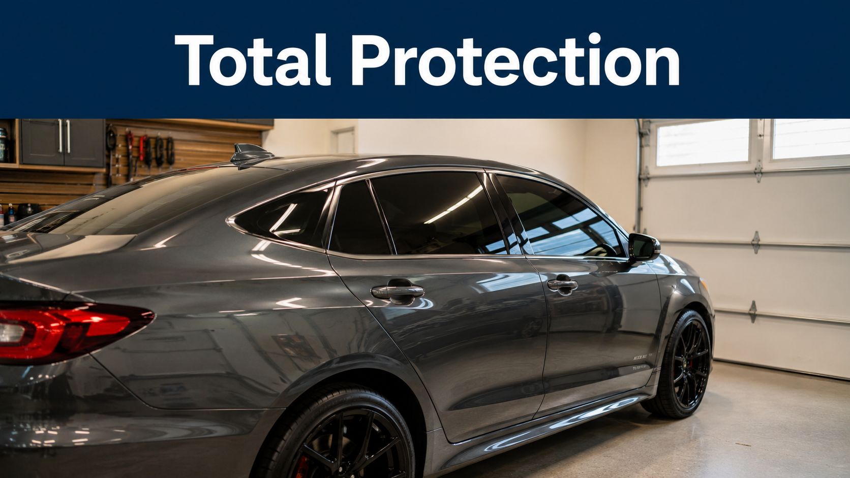 A modern grey sedan parked inside a garage featuring professional automotive window tinting for total protection.