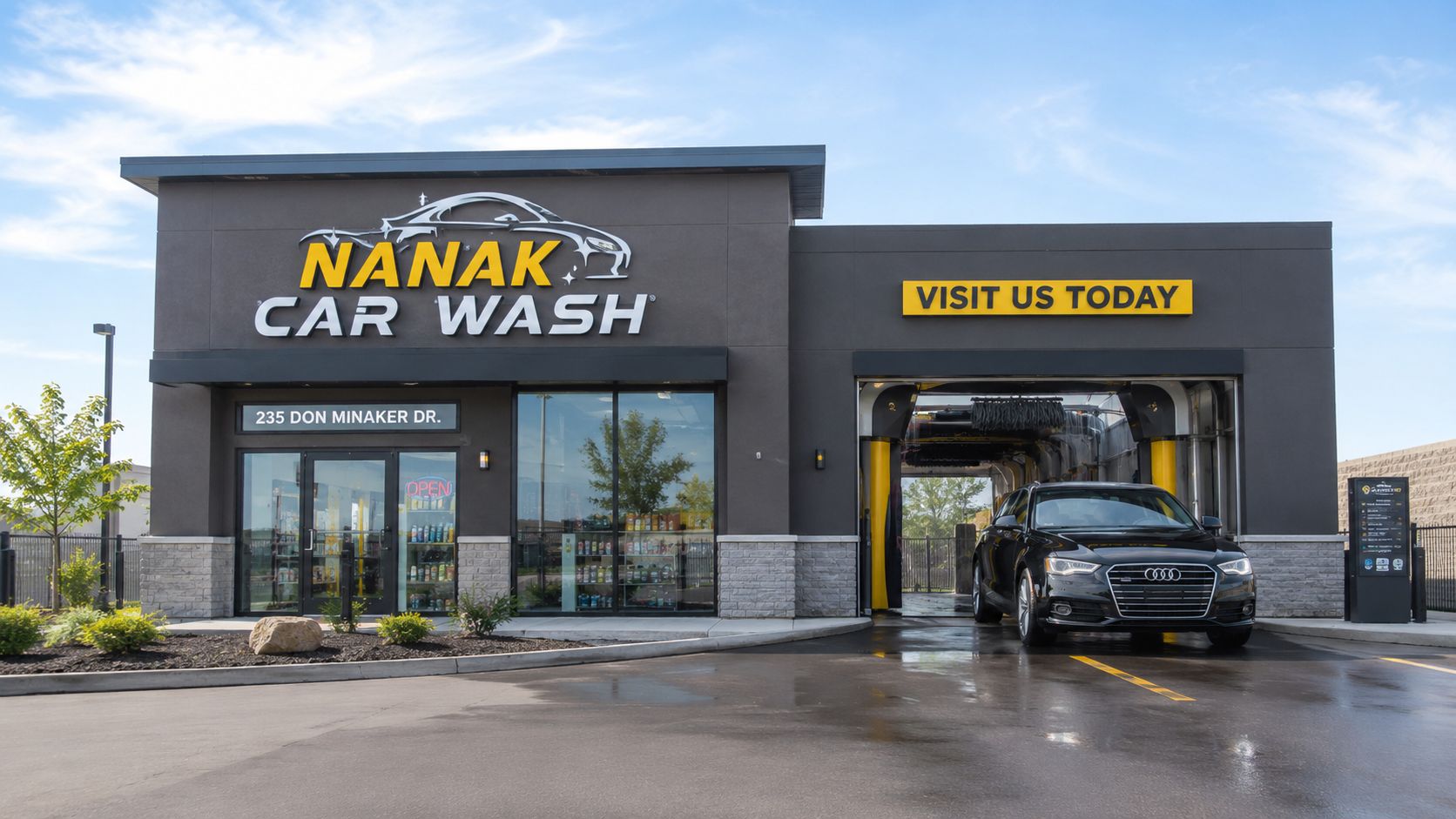 A sleek black Audi parked in front of the Nanak Car Wash building on a sunny day.