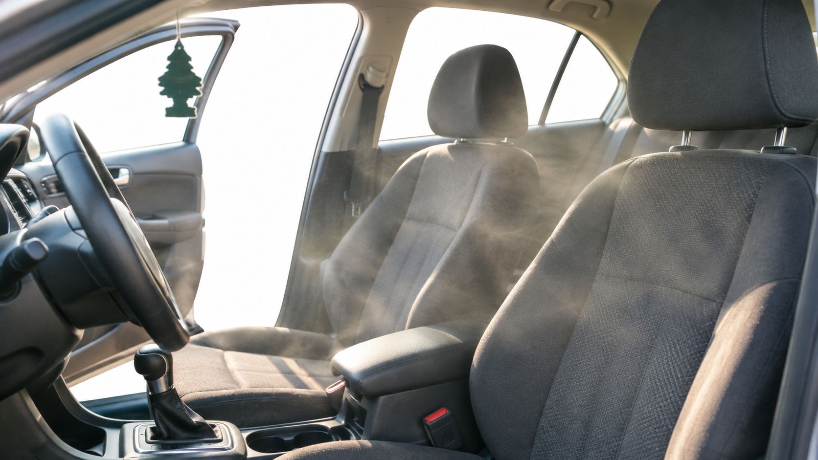 A professional car interior steam cleaning process removing odors and sanitizing the vehicle fabric seats.