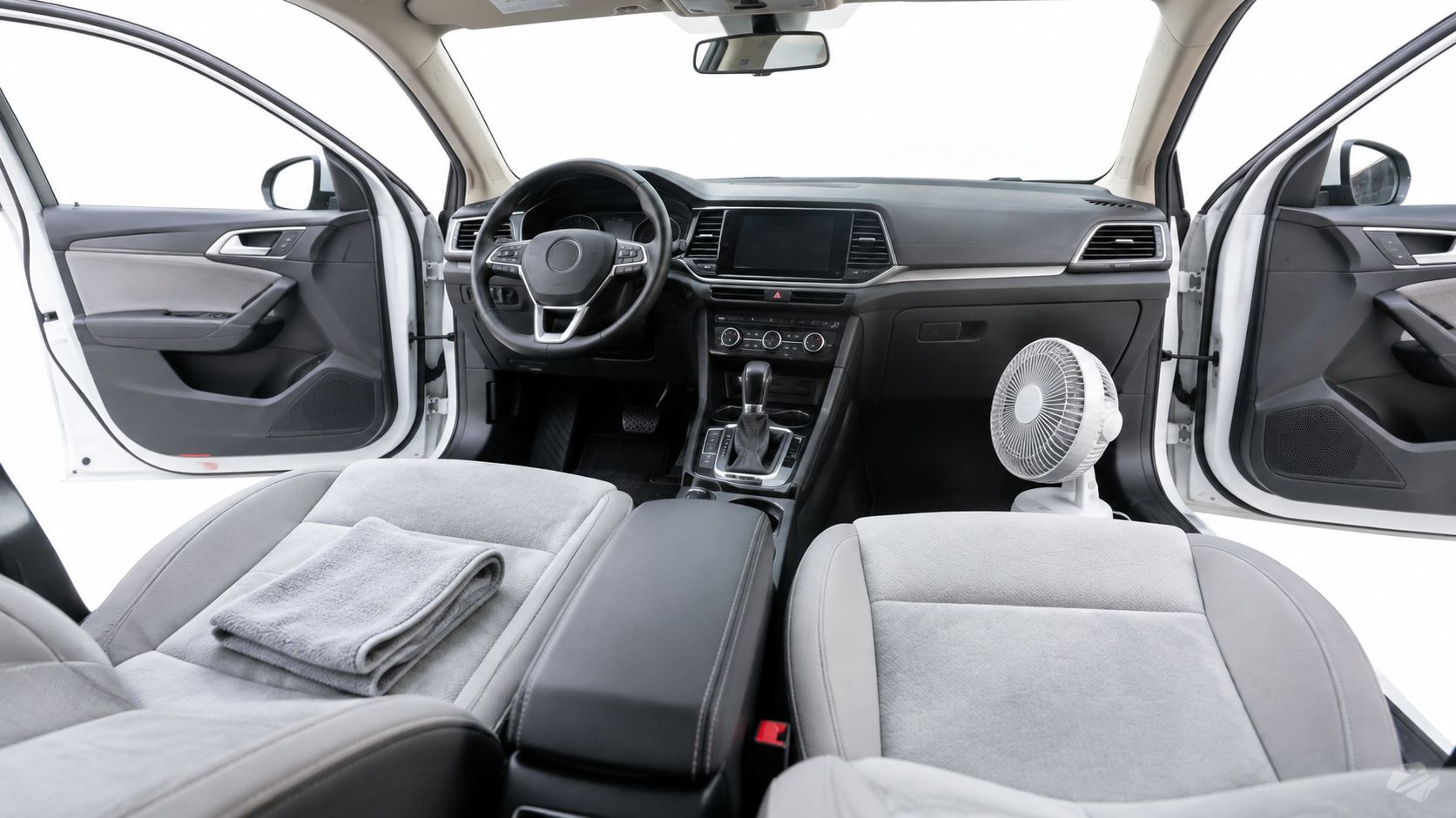 A modern car interior with grey fabric seats prepared for a deep cleaning process at home.