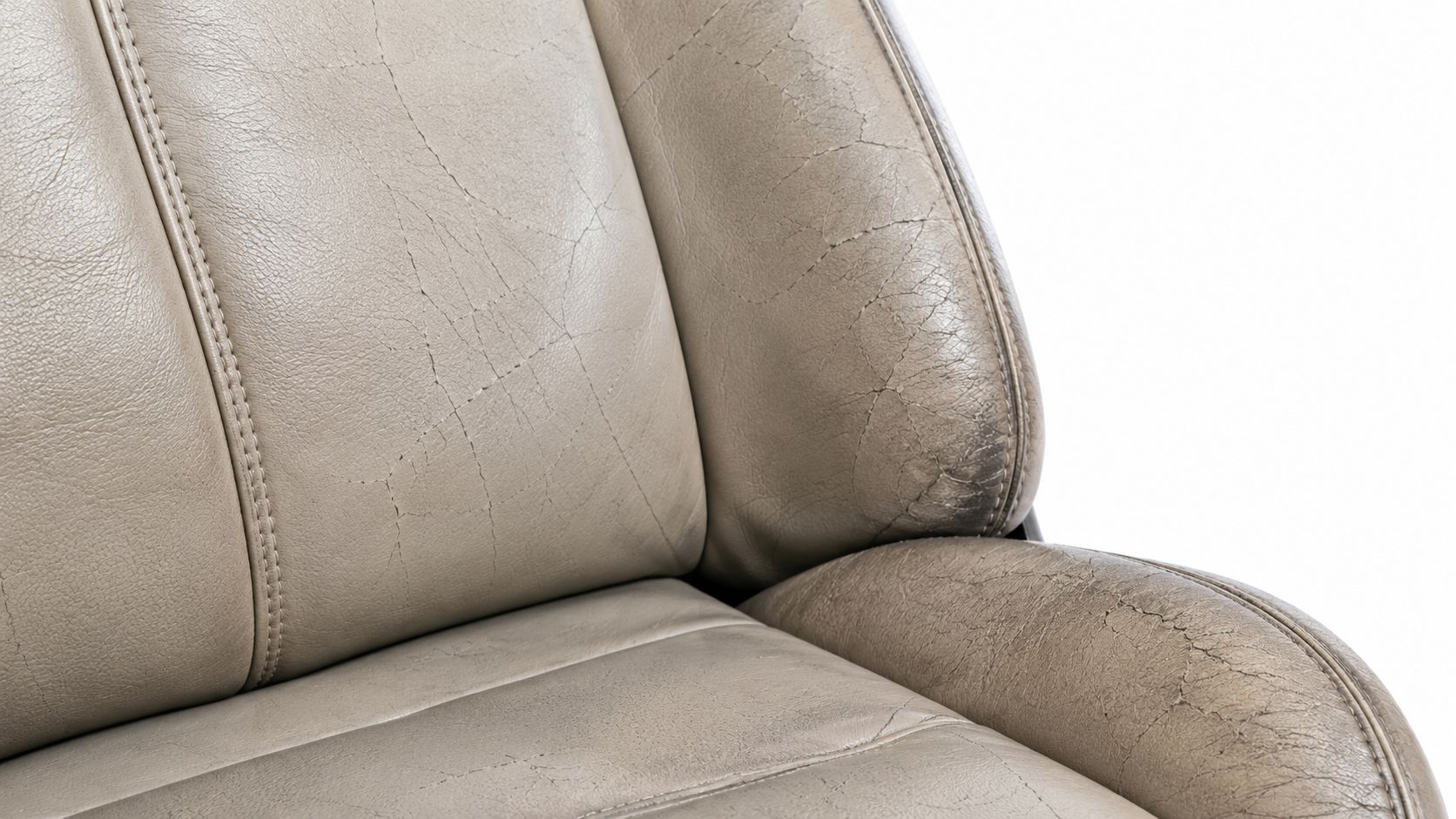 Worn and cracked beige leather upholstery on a car seat showing signs of aging and wear.