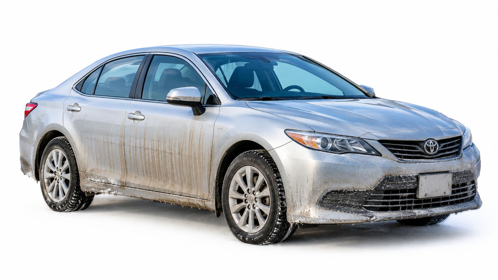 A dirty silver Toyota sedan covered in road grime and slush against a plain white background.